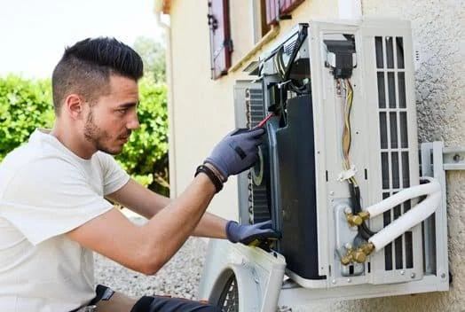Technician inspecting the open housing of an outdoor air conditioning unit