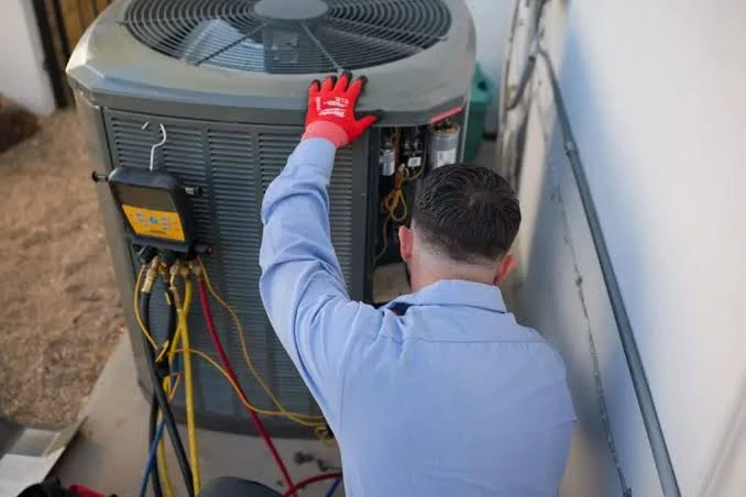 Technician examining the service panel of a residential outdoor HVAC unit
